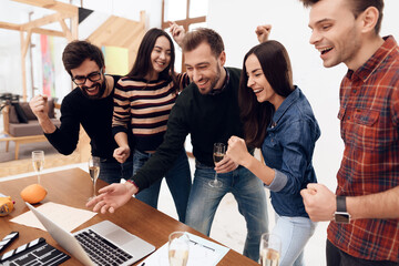 Cheerful company of people looking at a laptop. 