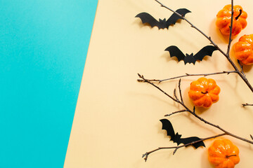 Halloween decorations with pumpkin and bats and branches on pastel beige blue background. Halloween concept. Flat lay, top view, copy space