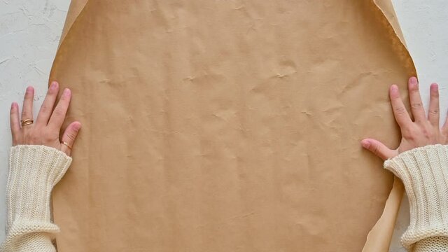 Female hands unroll gift wrapping paper. Christmas crafts. Top view.