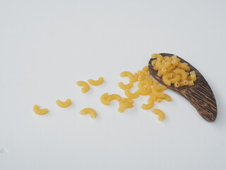 Raw macaroni on brown wooden spoon and white wooden background, Top view with copy space.