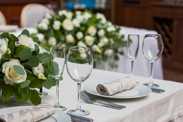Glass wine glasses stand on the table against a background of flowers
