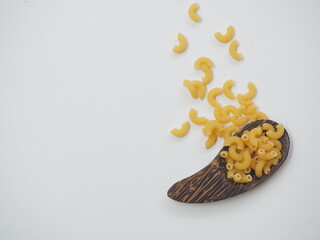 Raw macaroni on brown wooden spoon and white wooden background, Top view with copy space.