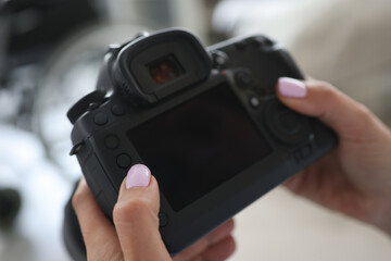 Female hands are holding a camera in photo studio close-up. Repair services for camera technology concept.