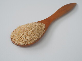 Coarse brown jasmine rice ( milled rice imperfectly cleaned, unpolished or half milled rice ) on wooden spoon background, Healthy food and diet concept.