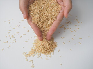 Woman's hand holding Coarse brown jasmine rice ( milled rice imperfectly cleaned, unpolished or half milled rice ) on white wooden background, Healthy food and diet concept.