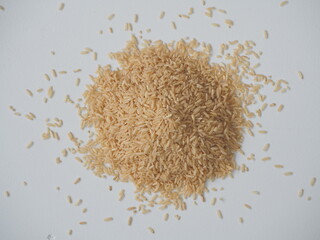 Coarse brown jasmine rice ( milled rice imperfectly cleaned, unpolished or half milled rice ) on white wooden background, Healthy food and diet concept.