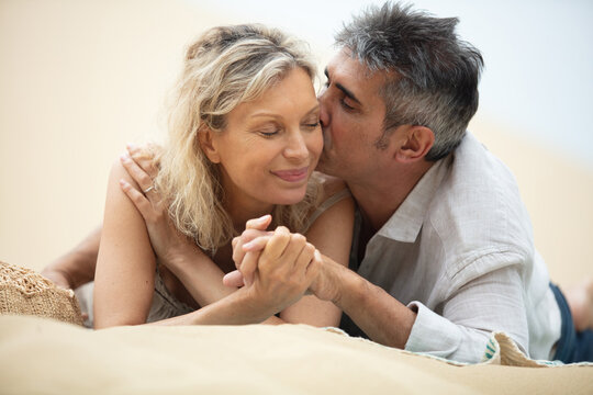 kissing senior couple lying together on the beach