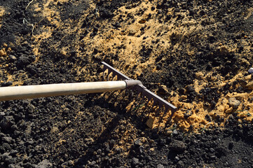 working garden rake is used to mix soil and sand for the vegetable garden