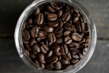 Fototapeta premium Fresh arabica coffee beans in a little jar on a wooden table. Fresh coffee beans.