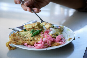 Spicy Egg Omelet on a white plate with Chilli and slice Onion 