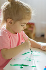 little girl painting with paintbrush and colorful paints.