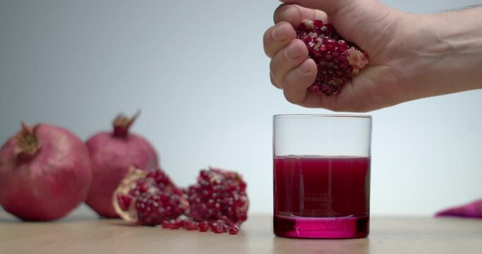 Man hand squeezing pomegranate to make fresh juice. Healthy vitamin drink for special diet. 