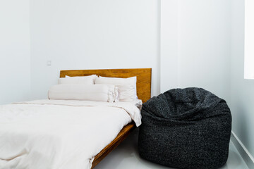 Gray bean bag inside bedroom next to comfy bed. Minimalist bedroom interior design. Minimalist bedroom interior design.