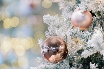 Fototapeta na wymiar Decorated artificial christmas tree on soft blurred golden lights. Baubles on tree branch. Happy new year or merry christmas card. Festive holiday background. Banner, copy space