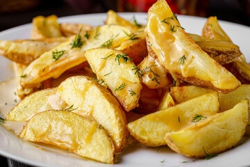 Country style potatoes with melted cheese. Serving food in a restaurant on a white plate. Background image.