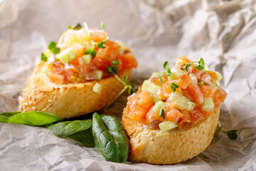 Italian Cuisine. Salmon baguette bruschetta, tomato and avocado. Serving food in a restaurant on parchment. Background image.