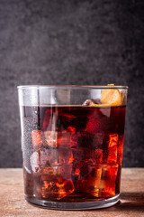 Boulevardier cocktail and orange zest on rusty floor