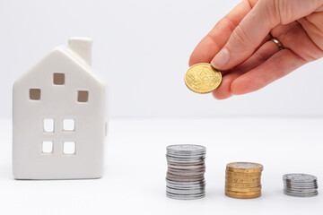Concept of investment in property, hand putting coin with white house on background. Taking loan in...