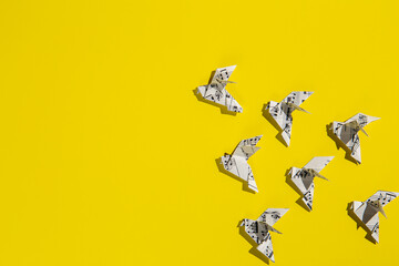 Flock of flying origami doves on yellow background. Origami birds of music paper. Concept of festive music postcard.