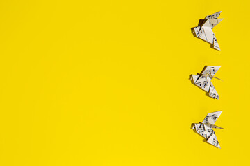 Flying origami doves on yellow background. Origami birds from music paper. Concept of festive music postcard.