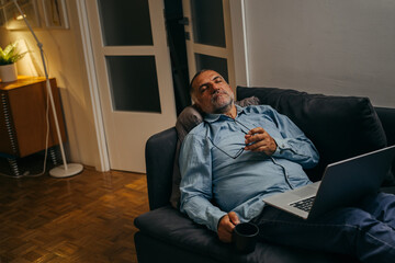 middle aged senior fall asleep while relaxing on sofa at his home