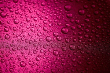 Hot pink water drops on a glitter surface, abstract macro photography