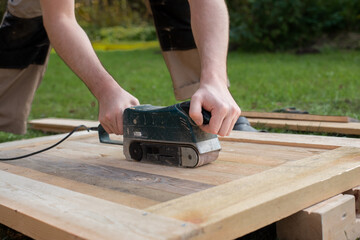 worker grinds a wooden product