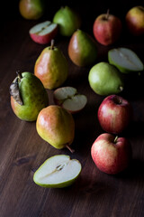 Various apples and pears against a dark background and lit from the side.