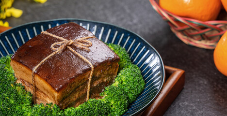 Dong Po Rou (Dongpo pork meat) in a beautiful plate with green vegetable, traditional festive food for Chinese new year cuisine meal, close up.
