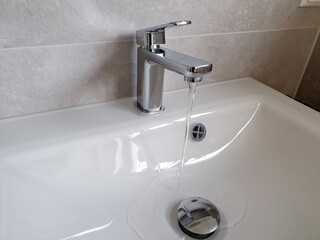 Fliesendes Wasser aus dem Wasserhahn in ein Waschbecken