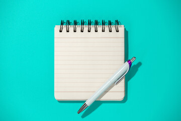 notepad and pen on blue background, top view