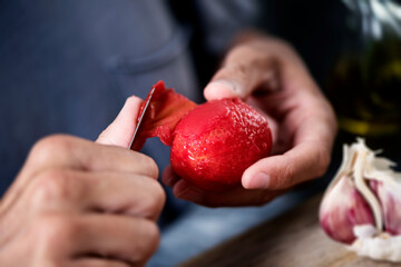 man peeling a scalded tomato