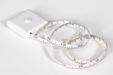 Small white tape measure for home use, with lock button, uncoiled to about 30 inches, on white background