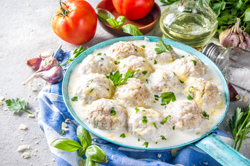 Homemade creamy white chicken meatballs. Classic Swedish meatballs with creamy cheesy sauce, with parmesan cheese and parsley, in skillet on grey stone table background