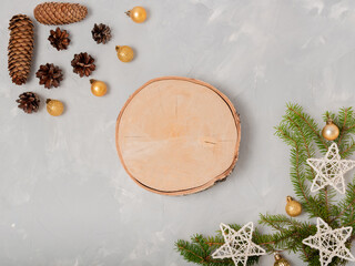 Obraz na płótnie Canvas Light New Year's composition. Pine cones, fir branches, festive stars and balls, wooden round saw cut in the center with space for product or text. Flat lay, top view