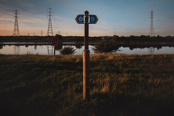 A signpost showing the Ribble Way walking trail along the River Ribble in Preston, UK at sunset