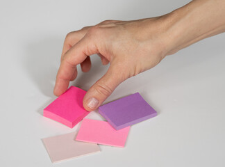 Female hand selecting sticky from stacks of various shades of pink and purple, for organizing project