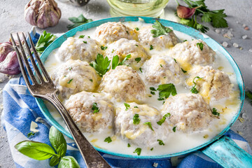 Homemade creamy white chicken meatballs. Classic Swedish meatballs with creamy cheesy sauce, with parmesan cheese and parsley, in skillet on grey stone table background