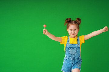 funny child with raised hands in the air. girl with a Lollipop is funny