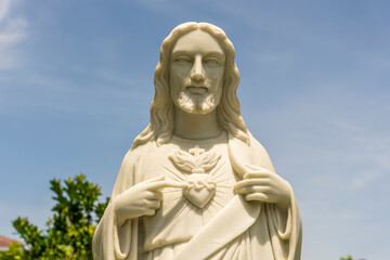 Fototapeta premium Detail of marble statue of Jesus Christ with heart in a temple and blue sky background in Danang, Vietnam