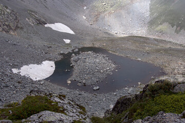 Alpine lake in a rocky valley. Valley in front of the Koshtan pass (3450 meters above sea level). Caucasus, Russia.