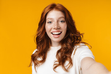 Image of redhead cheerful girl smiling and taking selfie photo