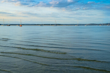 West Wittering, Chichester Harbour, South of England. Small waves gently lap onto the shore in the evening light.