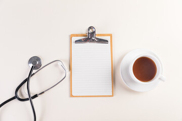 Top view shot of a notepad, medical stethoscope and a cup of a hot tea