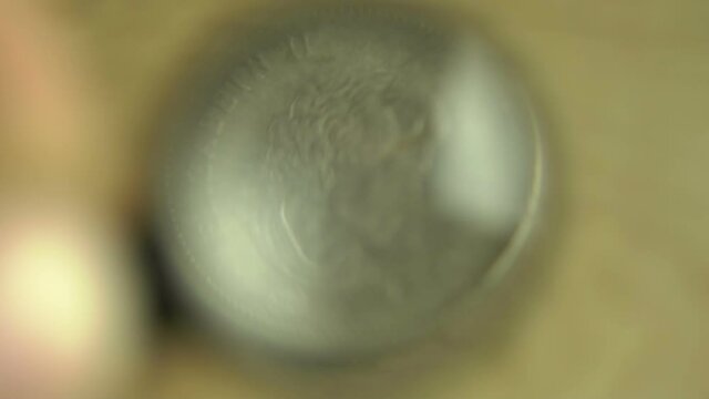 Numismatist Considers Old Coins Through Magnifying Glass Close Up