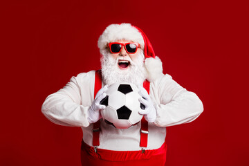 Portrait of his he attractive cheerful cheery glad fat white-haired Santa holding in hands throwing soccer ball hobby isolated bright vivid shine vibrant red burgundy maroon color background