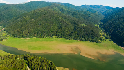 road under forest near a lake, aerial view in the daytime