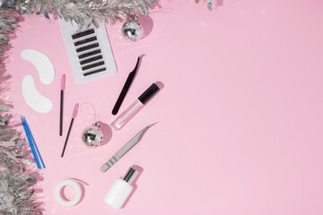 New year's flatley. Tools for eyelash extension on a pink background, top view. Patches, artificial eyelashes, brushes, glue, microbrushes. Christmas. Background for the lashmaker.
