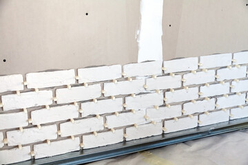 Pieces of the artificial bricks on the wall, installation in progress