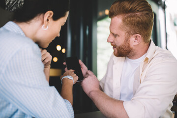 Man sharing mobile phone with female colleague